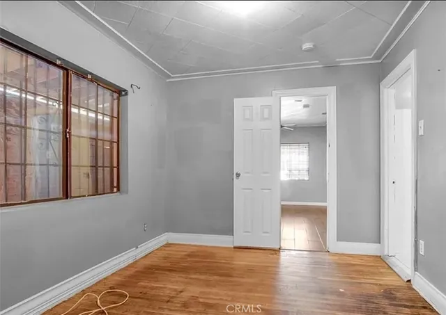 a view of empty room with wooden floor and fan