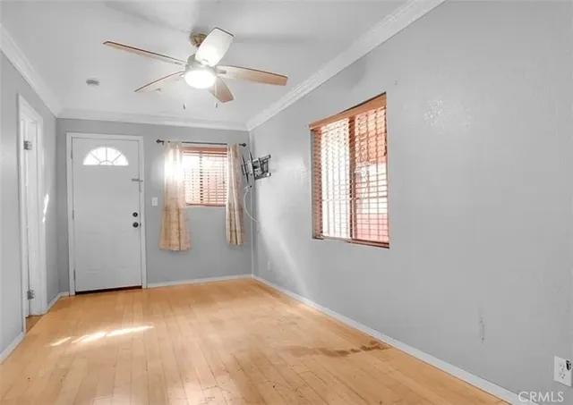 an empty room with chandelier fan and windows