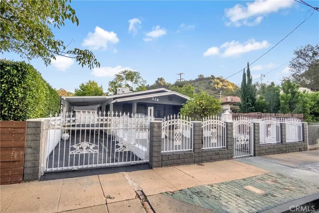 a view of a wooden house with large trees and wooden fence