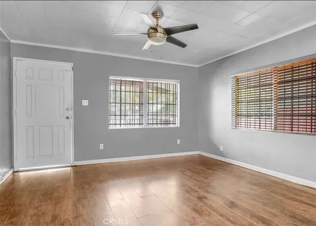 an empty room with wooden floor and windows