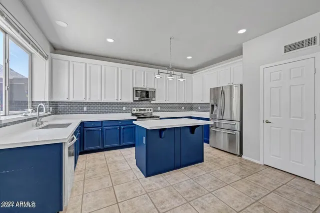 a kitchen that has a lot of cabinets and stainless steel appliances