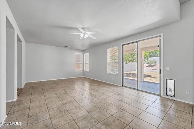 a view of an empty room with window and chandelier fan