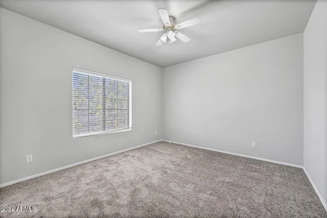 an empty room with windows and fan