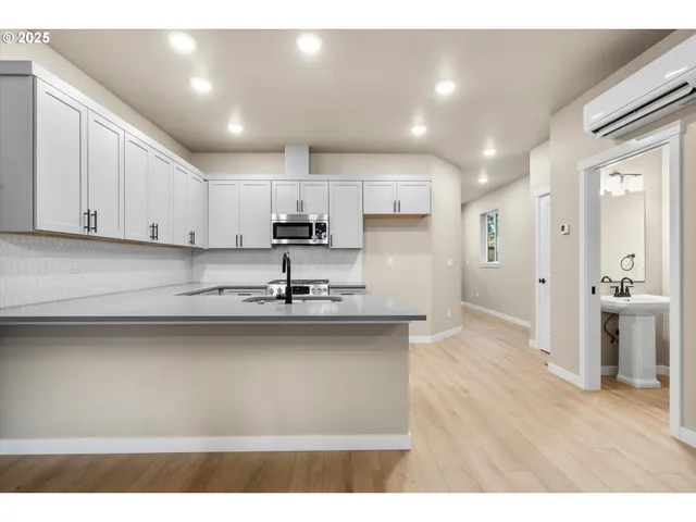 a view of an empty room with wooden floor and chandelier