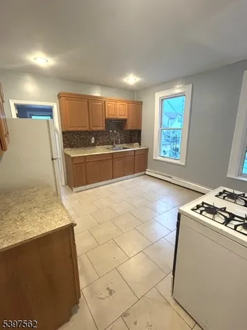 a large kitchen with kitchen island granite countertop a sink a stove a counter top space and cabinets