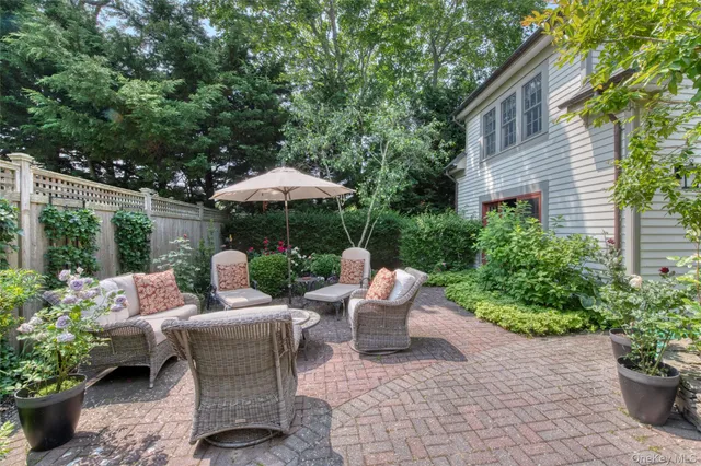 a view of a patio with couches table and chairs under an umbrella
