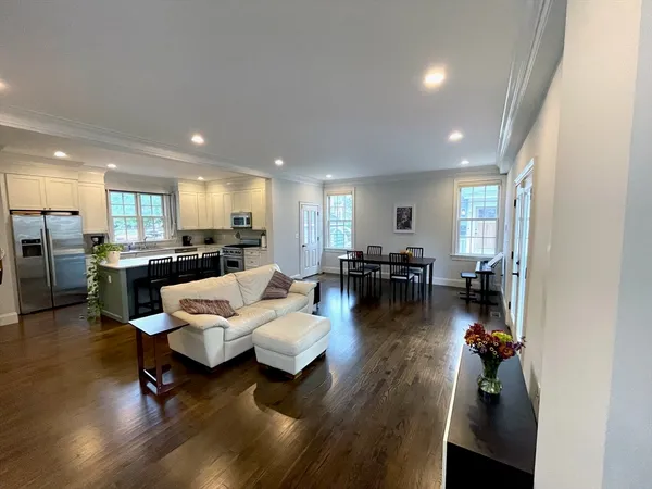 a living room with furniture kitchen view and a wooden floor