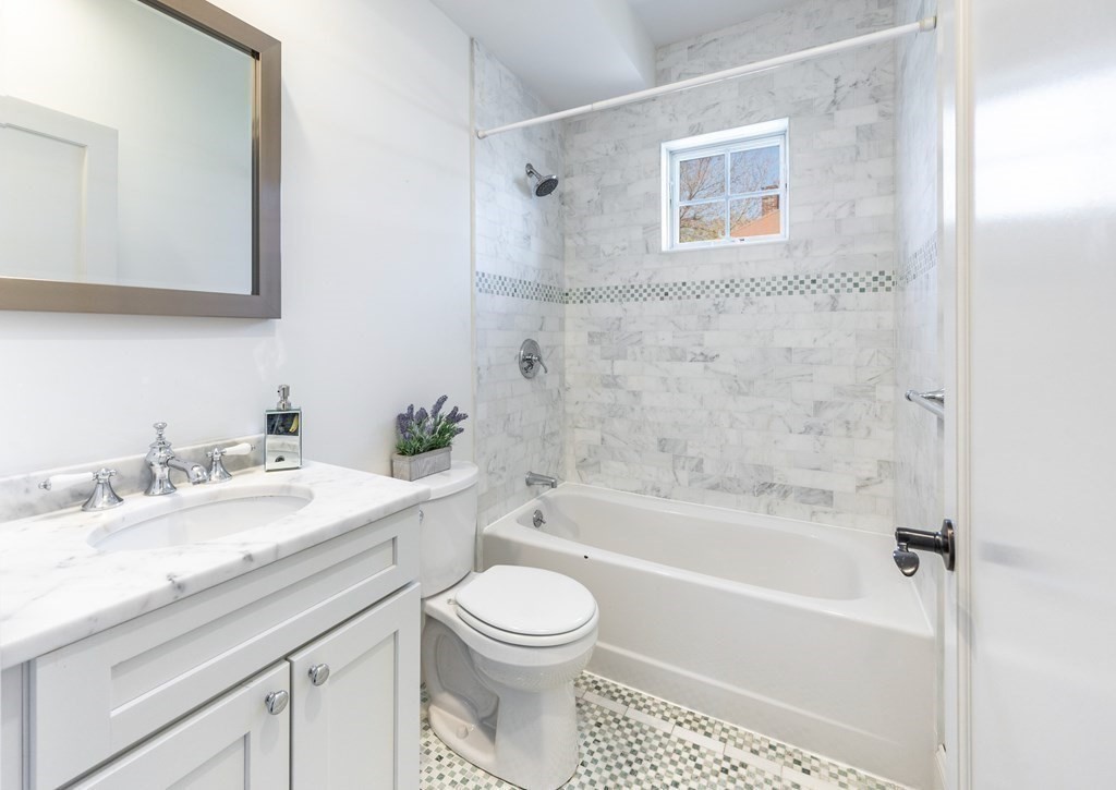 132 Rindge Avenue, Unit 1 Cambridge, MA 02140 - Photo 9 of 11 a bathroom with a granite countertop toilet sink and bathtub