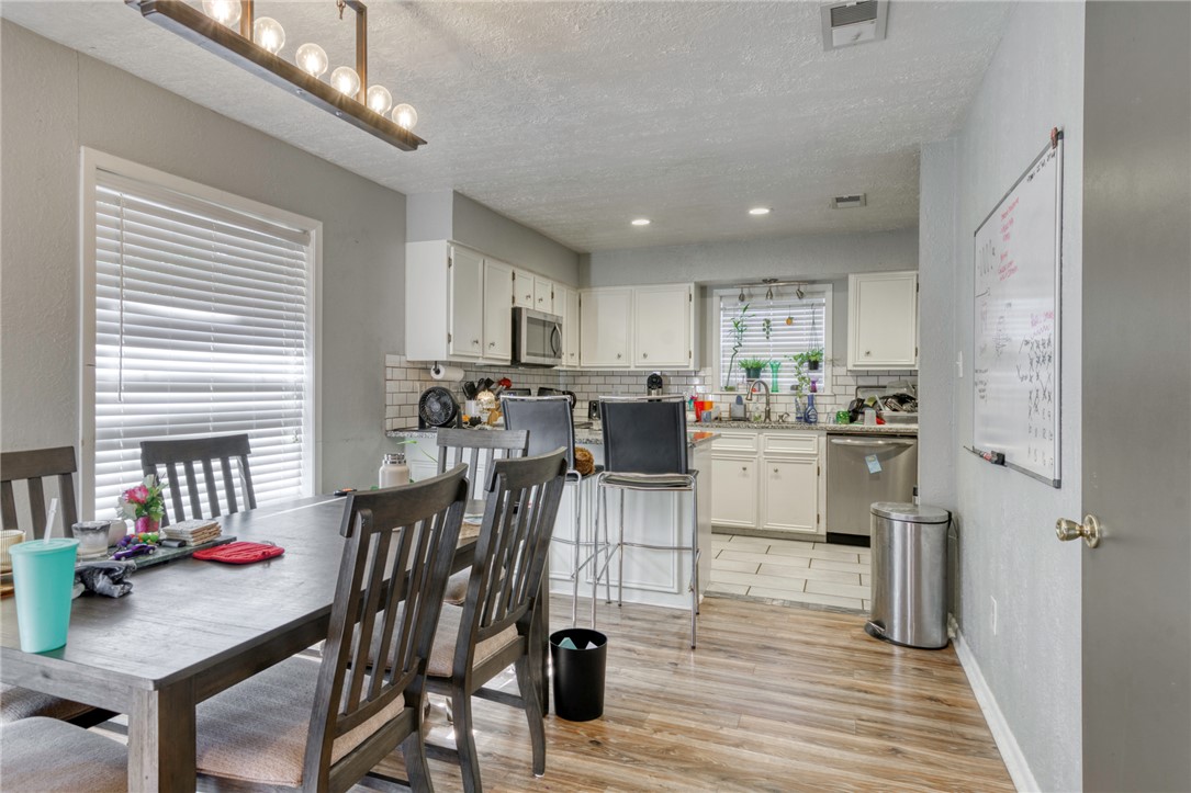 1410 Clement Court College Station, TX 77840 - Photo 5 of 16 a kitchen with stainless steel appliances kitchen island granite countertop a refrigerator a stove a sink dishwasher and a dining table with wooden floor