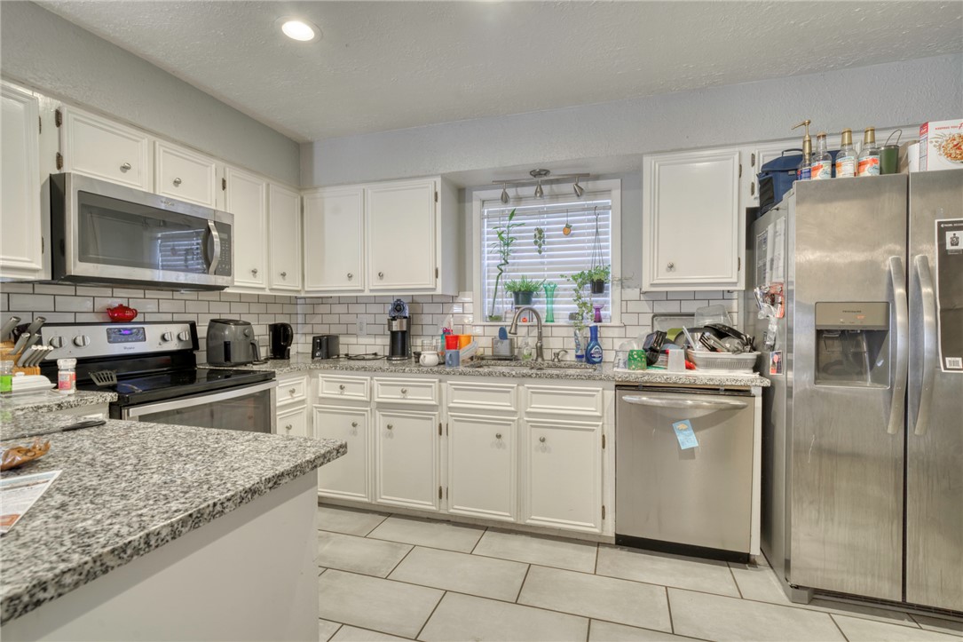 1410 Clement Court College Station, TX 77840 - Photo 6 of 16 a kitchen with stainless steel appliances granite countertop a refrigerator sink stove microwave and cabinets