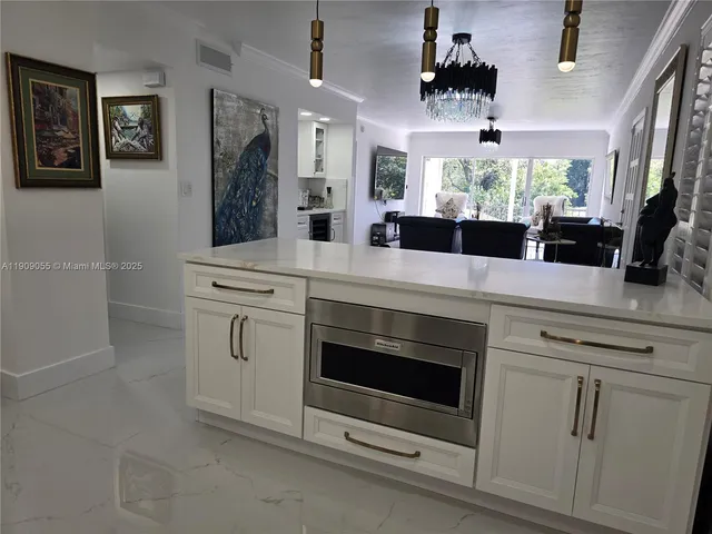 a kitchen with kitchen island a dining table chairs stainless steel appliances and cabinets