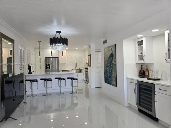 a kitchen with kitchen island a dining table chairs stainless steel appliances and cabinets