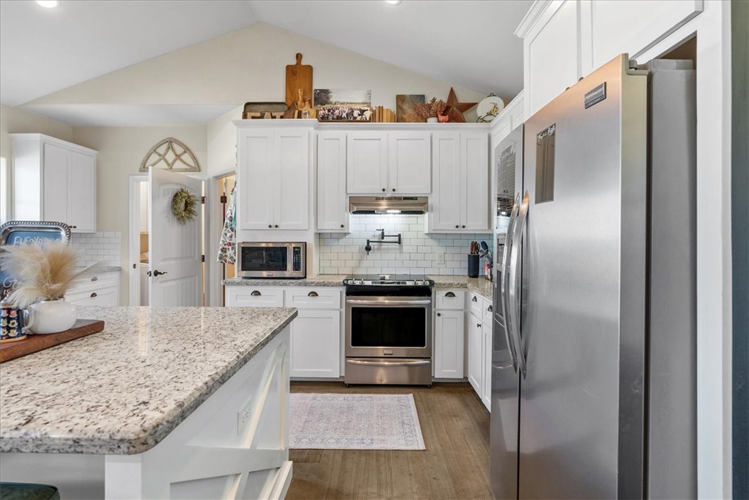 226 Private Road Alice, TX 78332 - Photo 8 of 40 a kitchen with stainless steel appliances granite countertop a refrigerator a oven and white cabinets with wooden floor