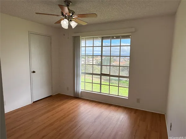 an empty room with wooden floor chandelier fan and windows