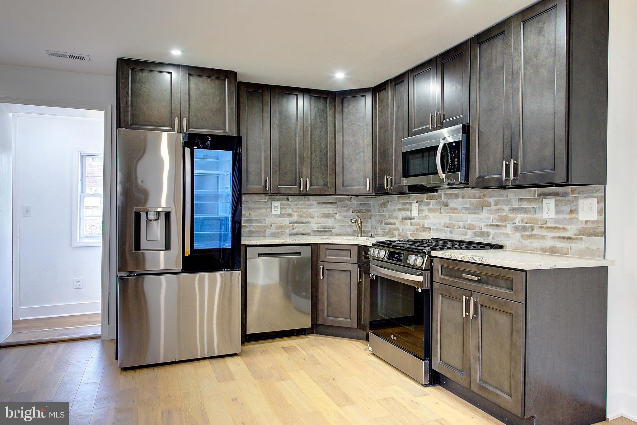 5736 Reedland Street Philadelphia, PA 19143 - Photo 7 of 22 a kitchen with granite countertop wooden cabinets a refrigerator and a stove top oven