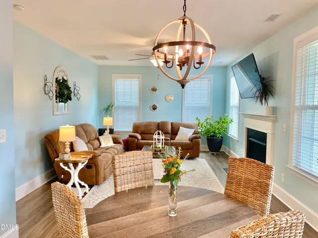 a view of a dining room and livingroom with furniture wooden floor a chandelier