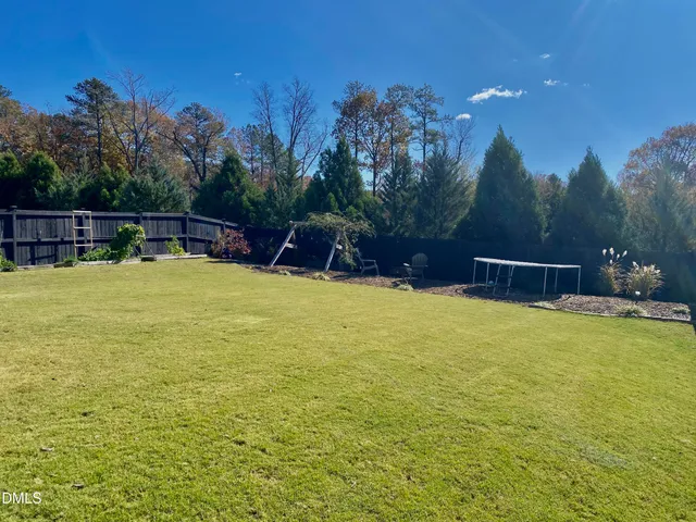 a view of a backyard with couches plants and large trees