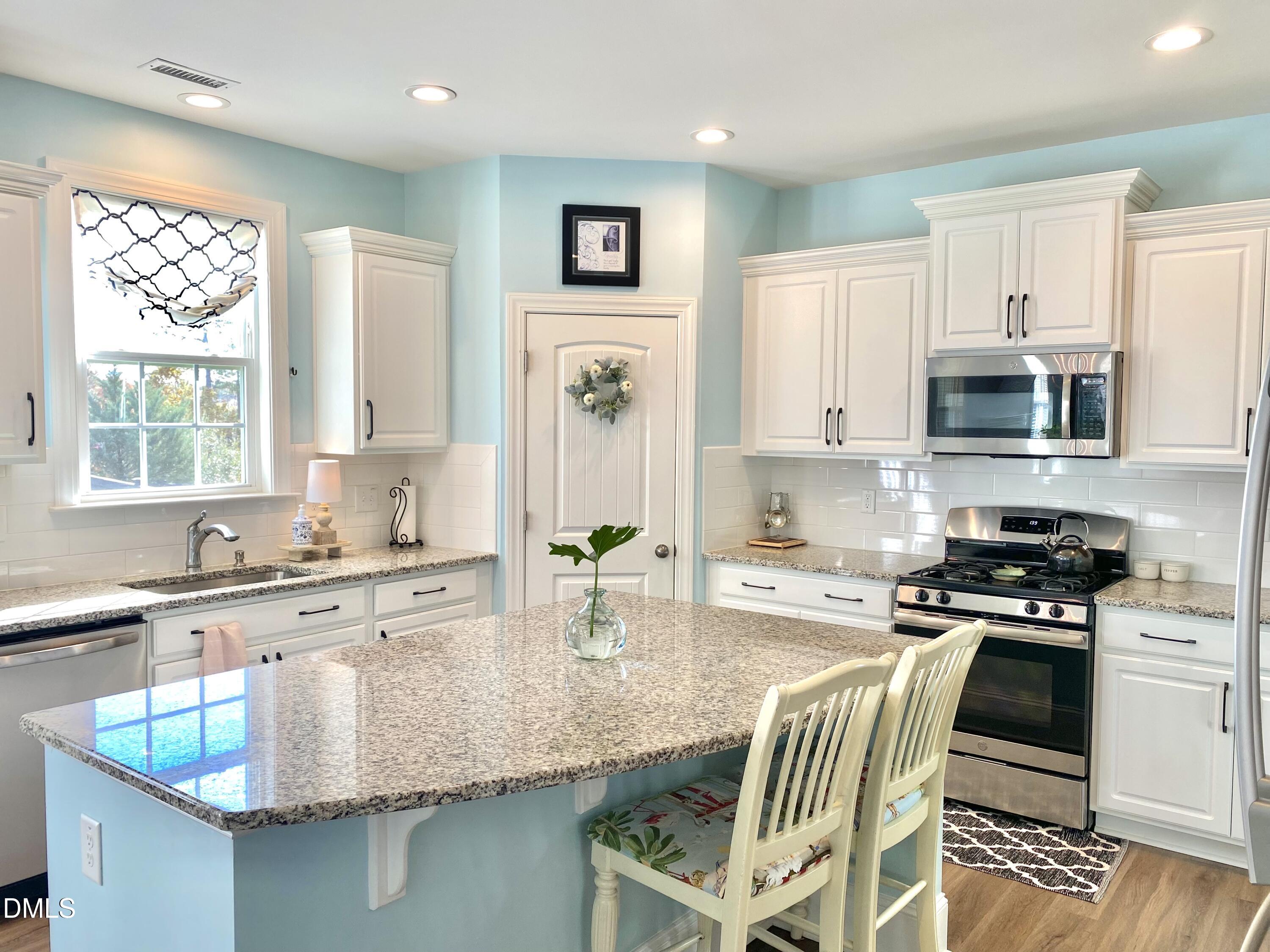 2913 Thurman Dairy Loop Wake Forest, NC 27587 - Photo 8 of 31 a kitchen with stainless steel appliances granite countertop a stove top oven a sink a dining table and chairs