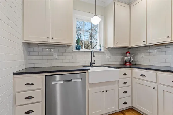 a kitchen with white cabinets and sink