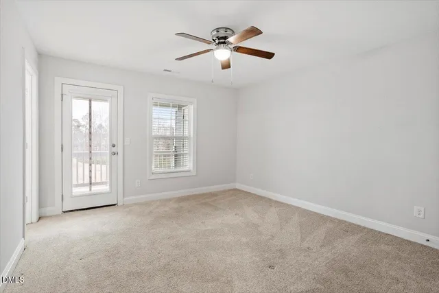 an empty room with chandelier fan and windows