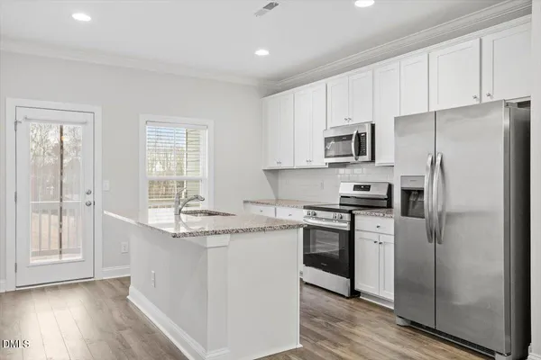 a kitchen with stainless steel appliances granite countertop a stove a sink and a refrigerator