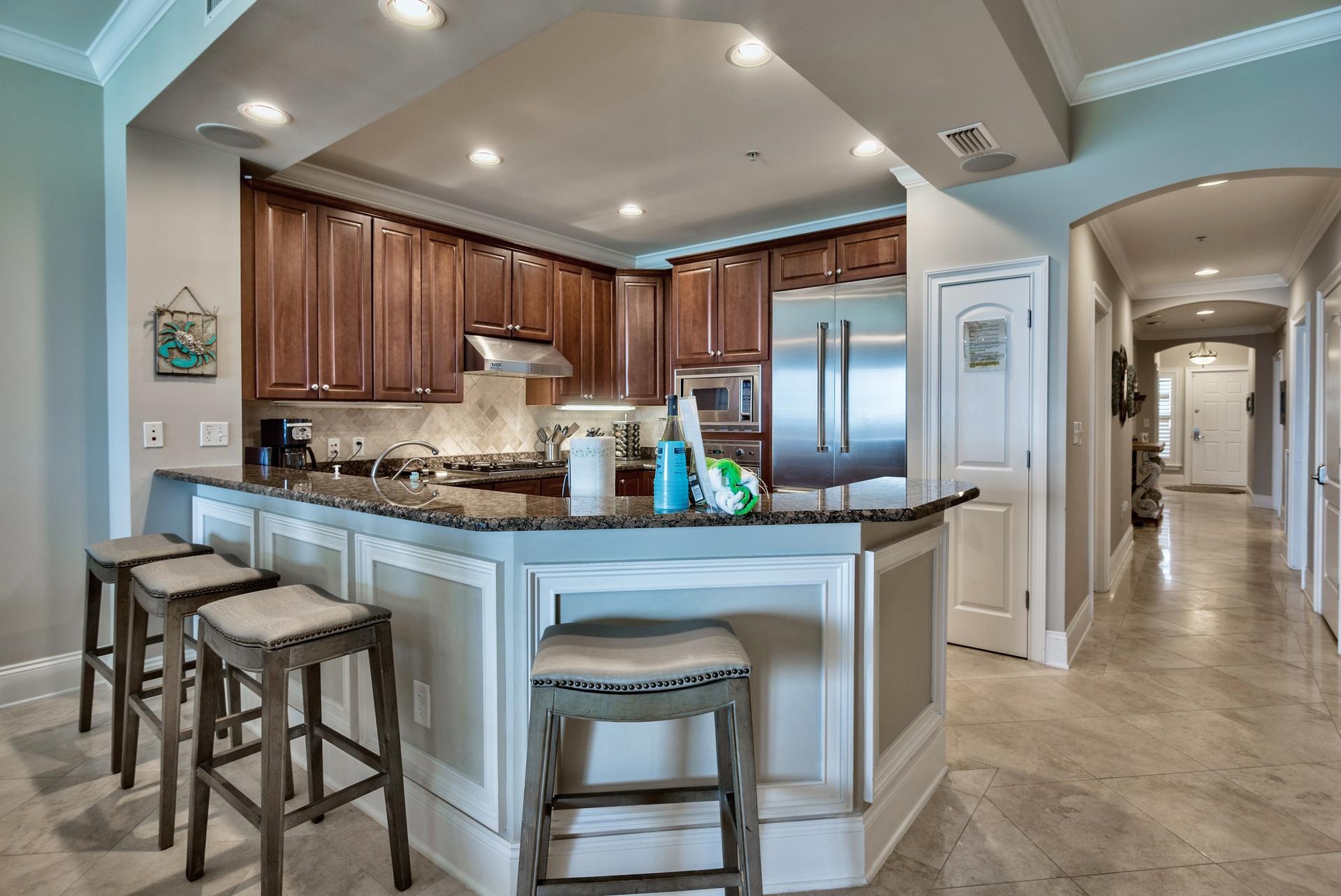 2421 West County Highway 30A, Unit C402 Santa Rosa Beach, FL 32459 - Photo 12 of 38 a kitchen with kitchen island granite countertop wooden cabinets and a refrigerator
