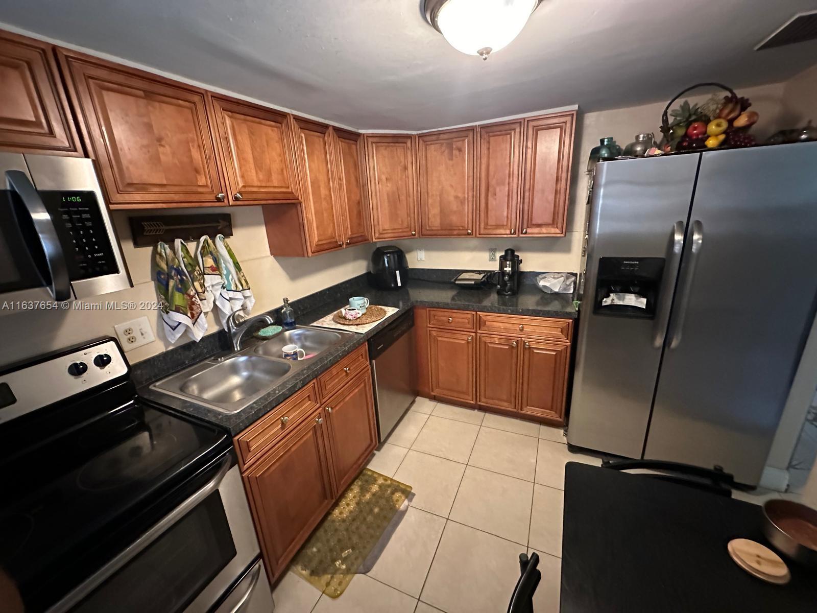 3195 Foxcroft Road, Unit F205 Miramar, FL 33025 - Photo 4 of 17 a kitchen with granite countertop a refrigerator stove and sink