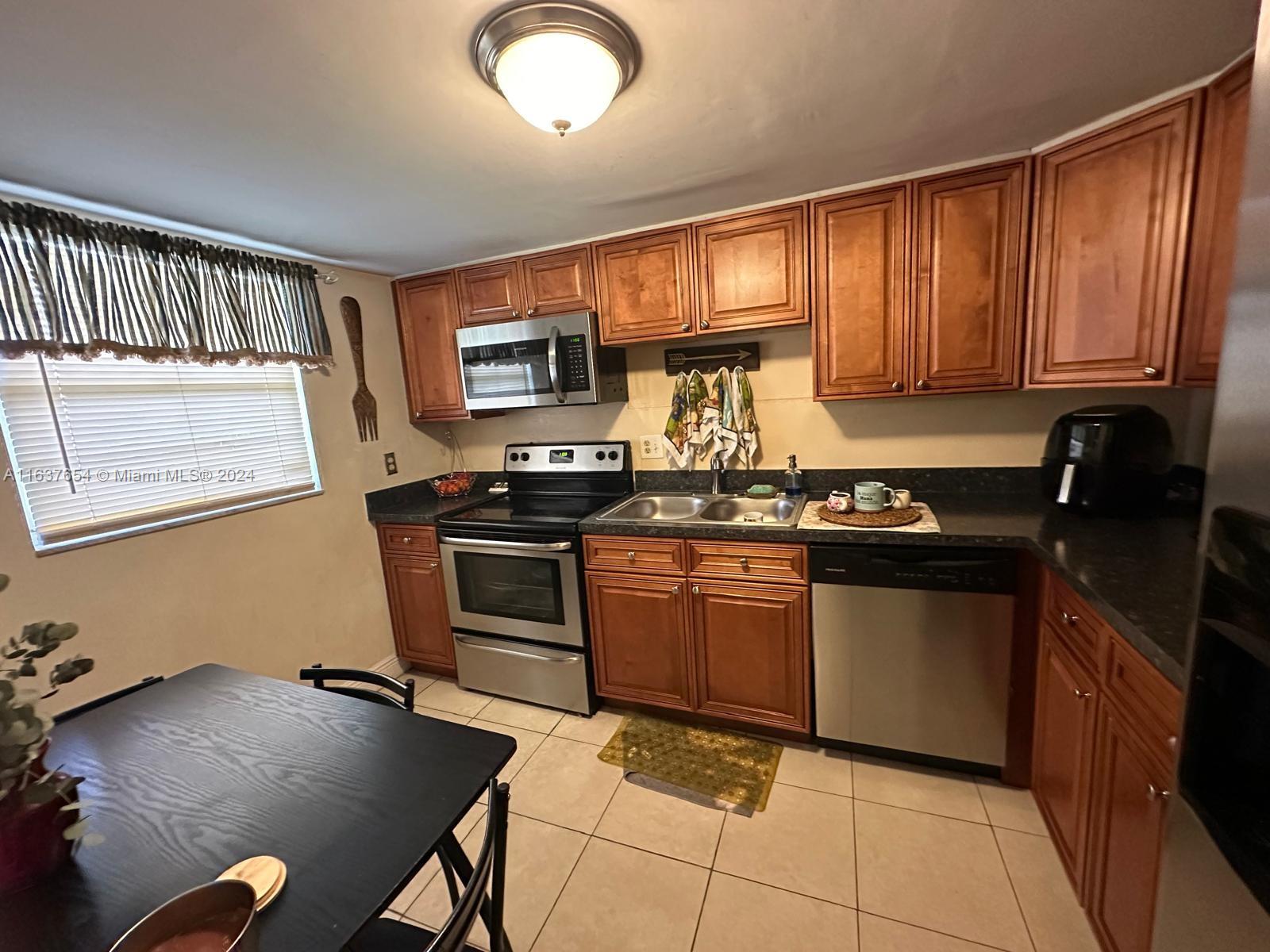3195 Foxcroft Road, Unit F205 Miramar, FL 33025 - Photo 5 of 17 a kitchen with granite countertop a stove cabinets and a sink