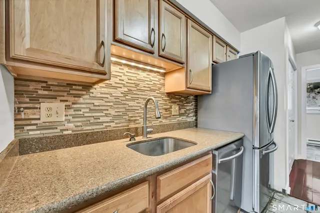 a kitchen with stainless steel appliances granite countertop a sink and a refrigerator