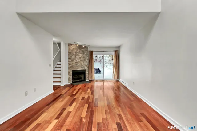a view of empty room with wooden floor and fireplace