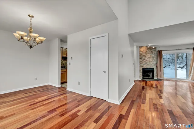 a view of an empty room with wooden floor fireplace and a window