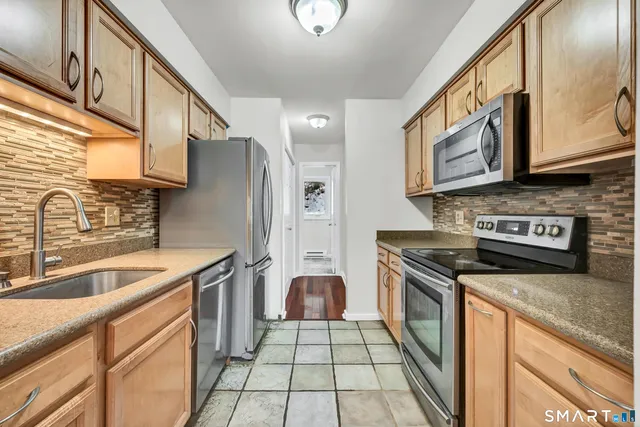 a kitchen with stainless steel appliances granite countertop a stove a sink and a microwave