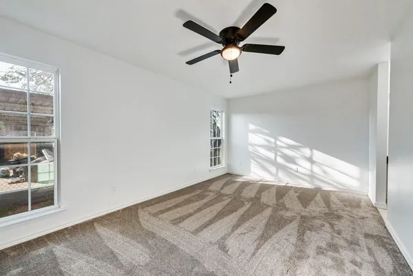 an empty room with windows and ceiling fan