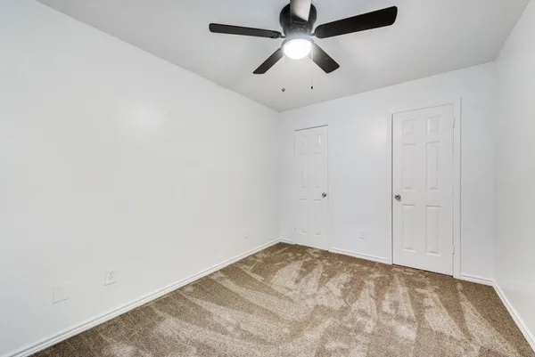 an empty room with a ceiling fan and carpet