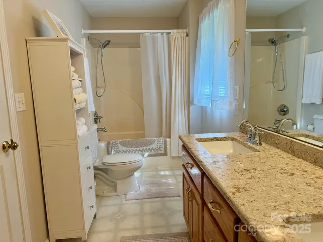 a bathroom with a granite countertop sink a toilet and shower