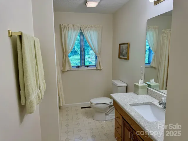 a bathroom with a granite countertop sink toilet and a mirror