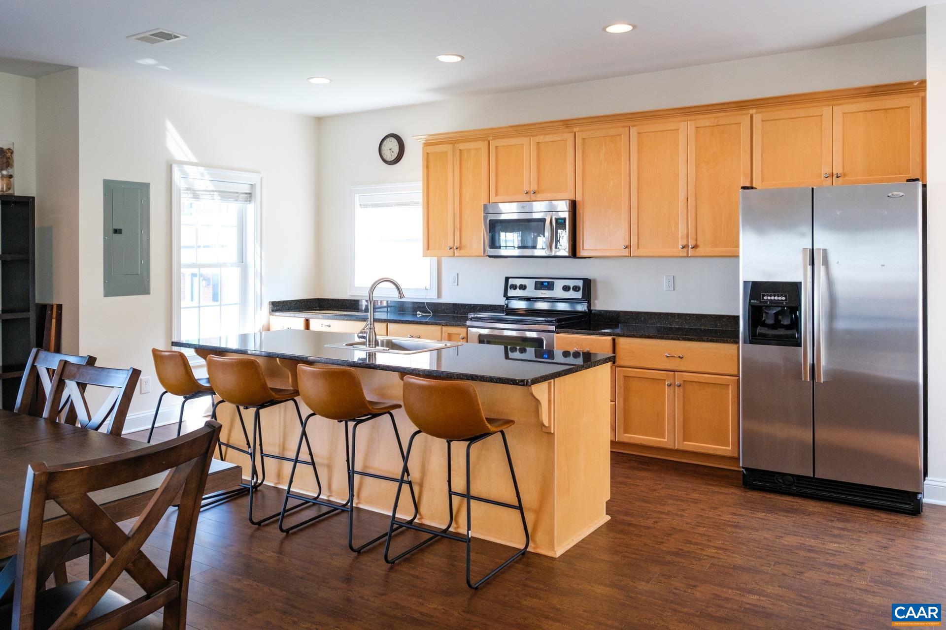 2138 Avinity Loop Charlottesville, VA 22902 - Photo 39 of 49 a kitchen with stainless steel appliances granite countertop a stove a sink a microwave a dining table and chairs