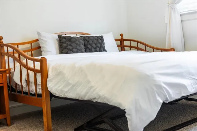 a bed sitting in a bedroom with a white comforter and pillows
