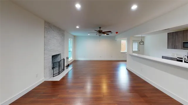 an empty room with wooden floor and a kitchen