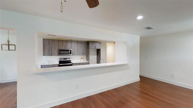 a kitchen with stainless steel appliances a stove top oven a sink with wooden floors and cabinets