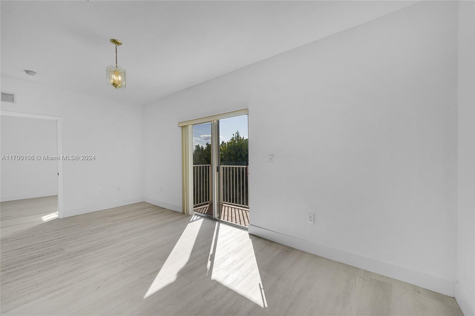 6940 Northwest 179th Street, Unit 3057 Hialeah, FL 33015 - Photo 16 of 32 an empty room with wooden floor and windows