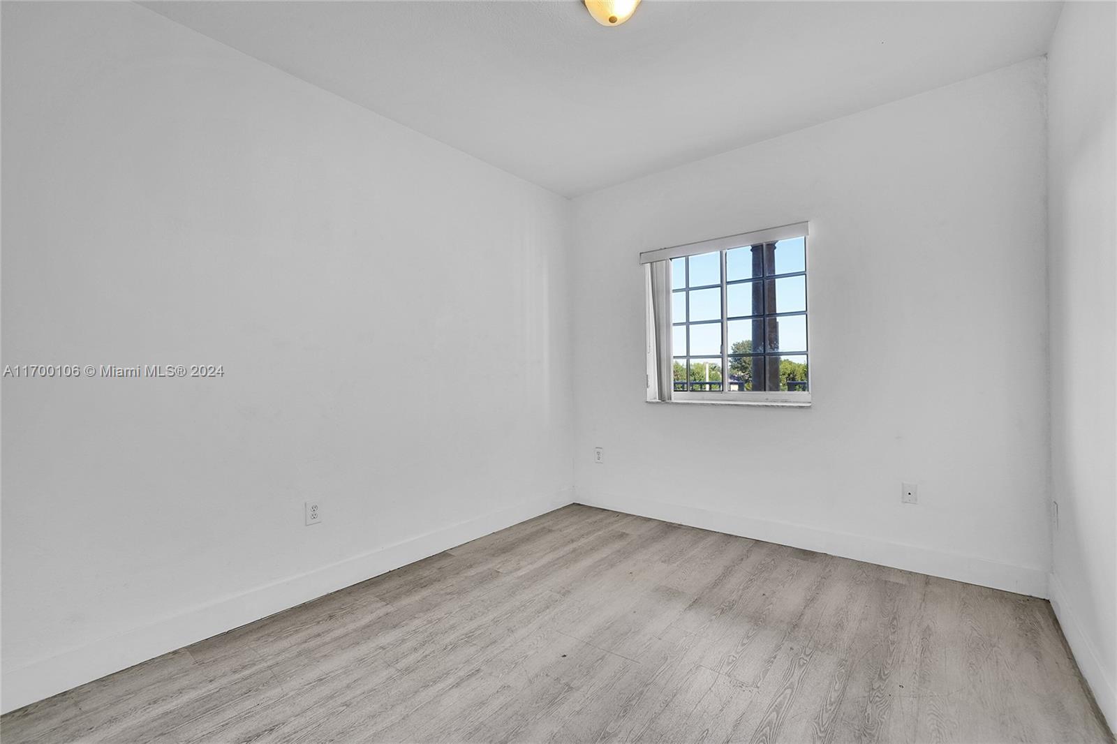 6940 Northwest 179th Street, Unit 3057 Hialeah, FL 33015 - Photo 25 of 32 an empty room with wooden floor and windows