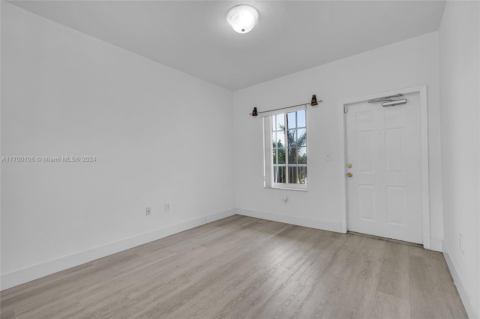 6940 Northwest 179th Street, Unit 3057 Hialeah, FL 33015 - Photo 28 of 32 an empty room with wooden floor and windows