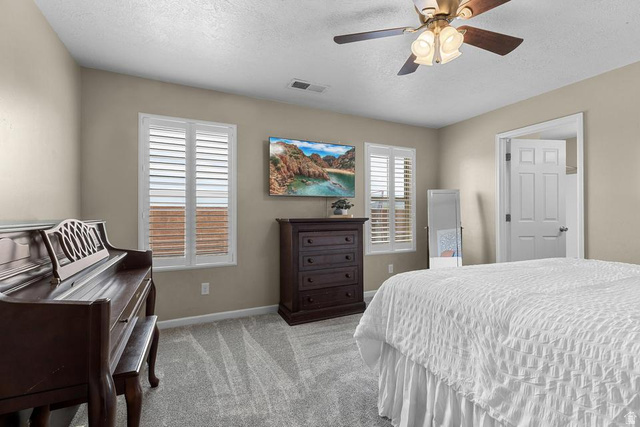 225 Falcon Court Ivins, UT 84738 - Photo 11 of 47 Bedroom featuring light colored carpet, multiple windows, a textured ceiling, and a ceiling fan
