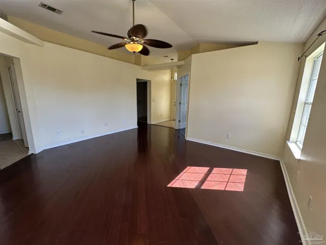 an empty room with windows and fan