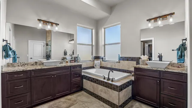 a spacious bathroom with a tub double sink and mirror