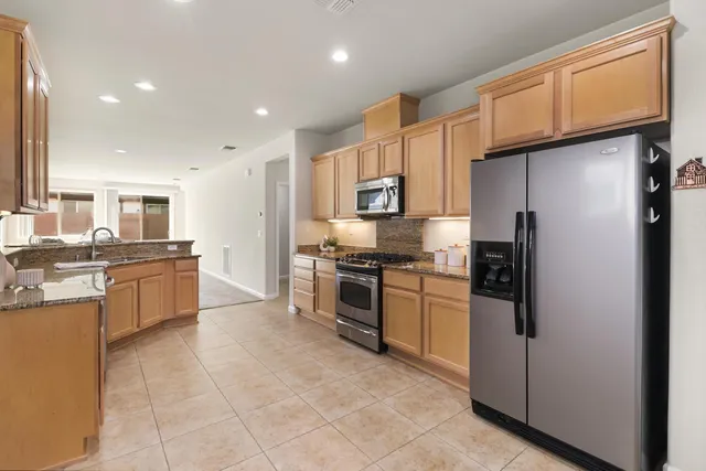 a kitchen with stainless steel appliances granite countertop a refrigerator a sink a stove top oven and a refrigerator