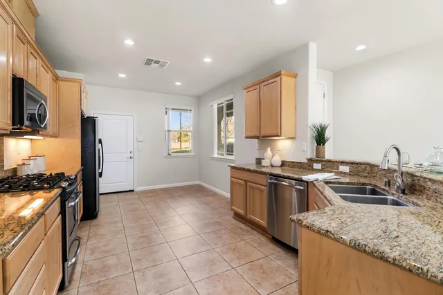 a kitchen with stainless steel appliances granite countertop a sink stove and refrigerator