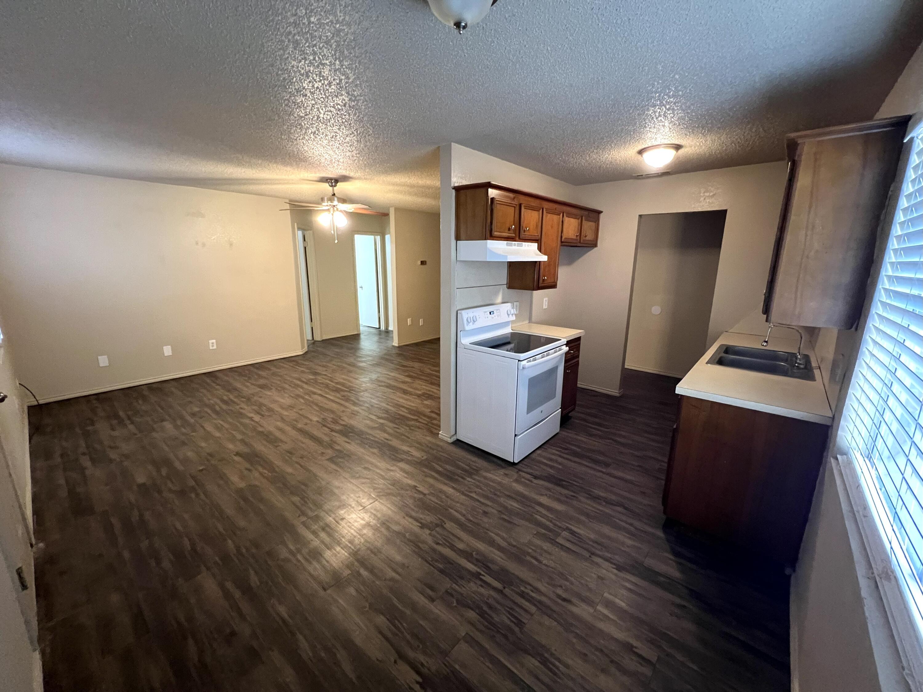 2403 88th Street Lubbock, TX 79423 - Photo 3 of 9 a view of kitchen and empty room with wooden floor