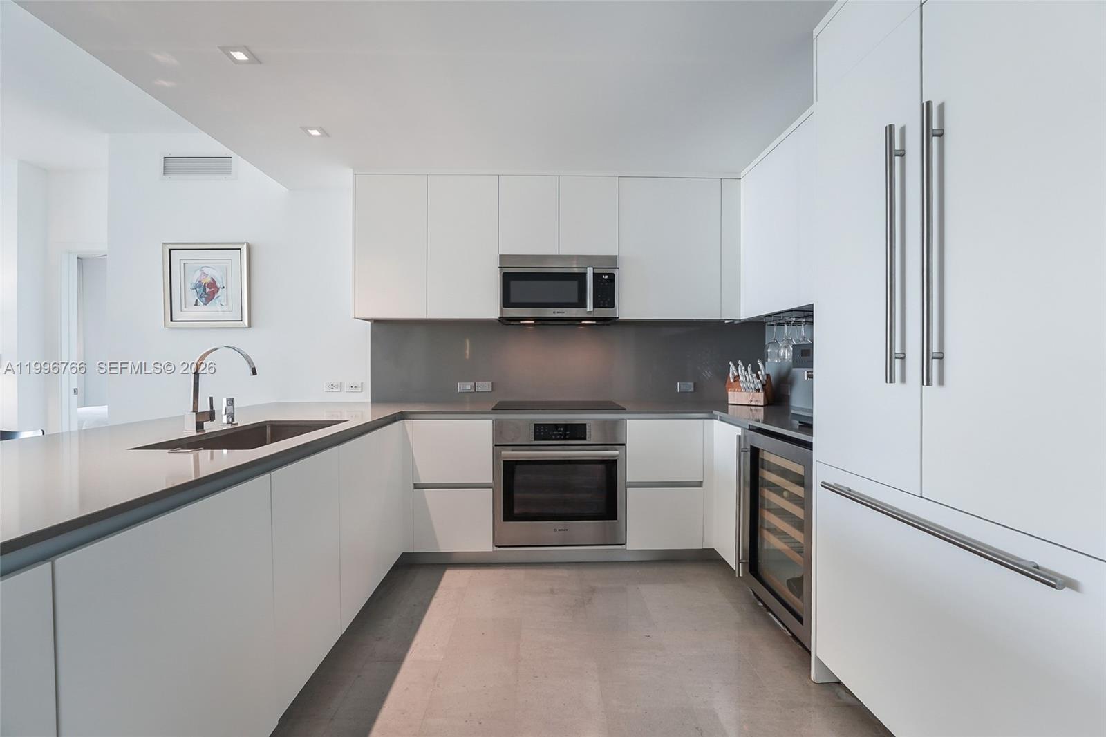 68 Southeast 6th Street, Unit 2104 Miami, FL 33131 - Photo 7 of 33 a kitchen with granite countertop white cabinets and stainless steel appliances